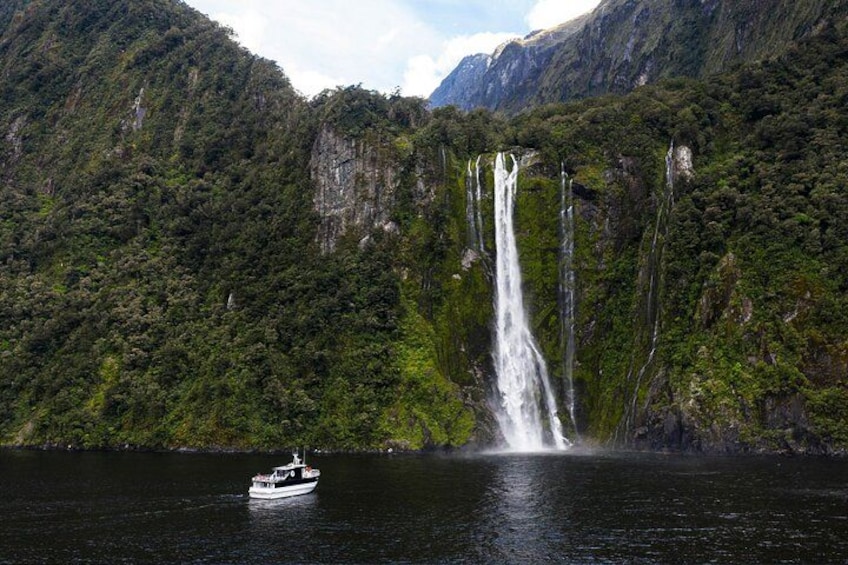 A boat on a calm lake with a large waterfall in the background. 5