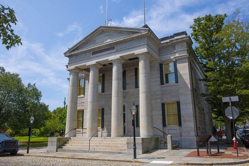 A neoclassical building with columns, a flagpole, and a stop sign. 5