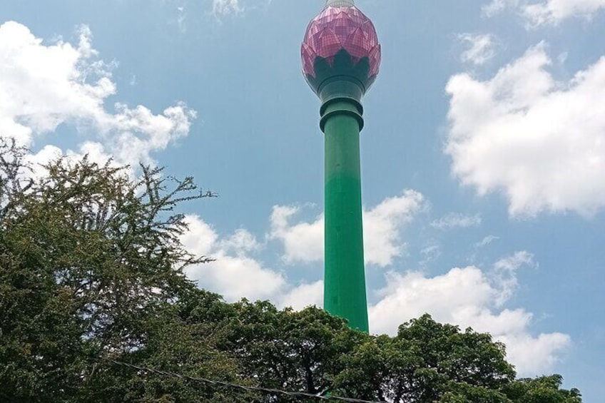 A tall tower with a spherical top, surrounded by trees and a clear sky. 2