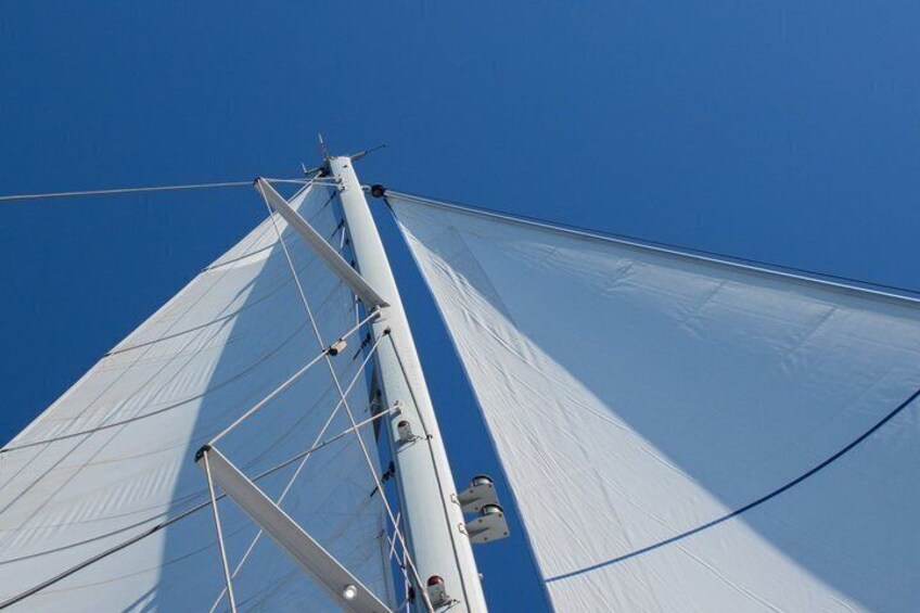 A sailboat's mast and sails against a clear blue sky. 4