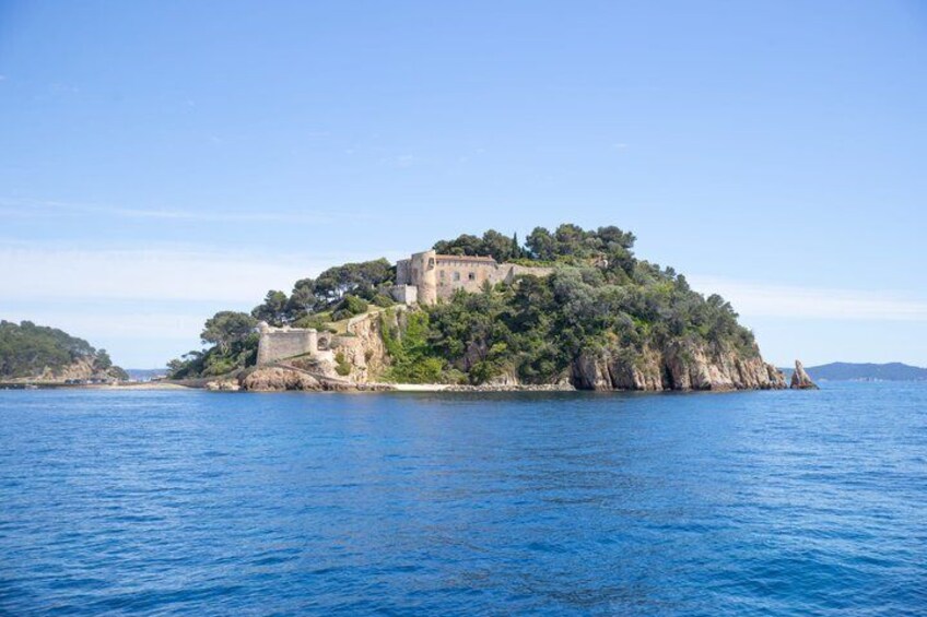A coastal island with a castle-like structure surrounded by greenery and rocky outcrops. 5