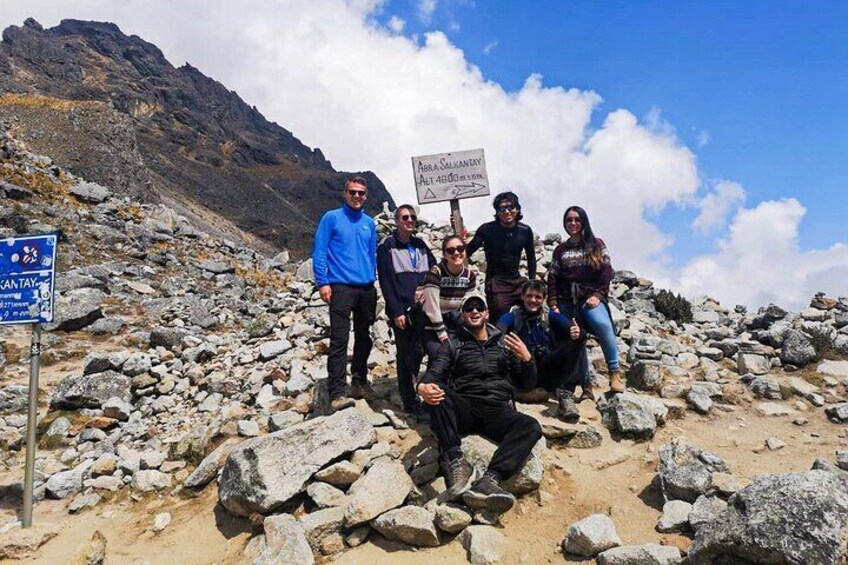 A group of people on a rocky mountain trail with a sign indicating the summit is 4000 meters. 2