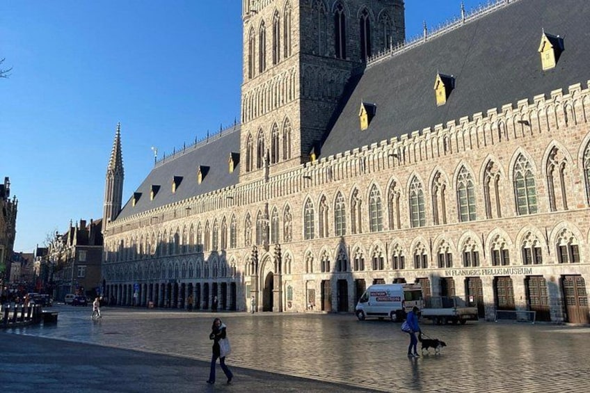 A historic building with Gothic architecture, a large open plaza, and a dog walking. 4