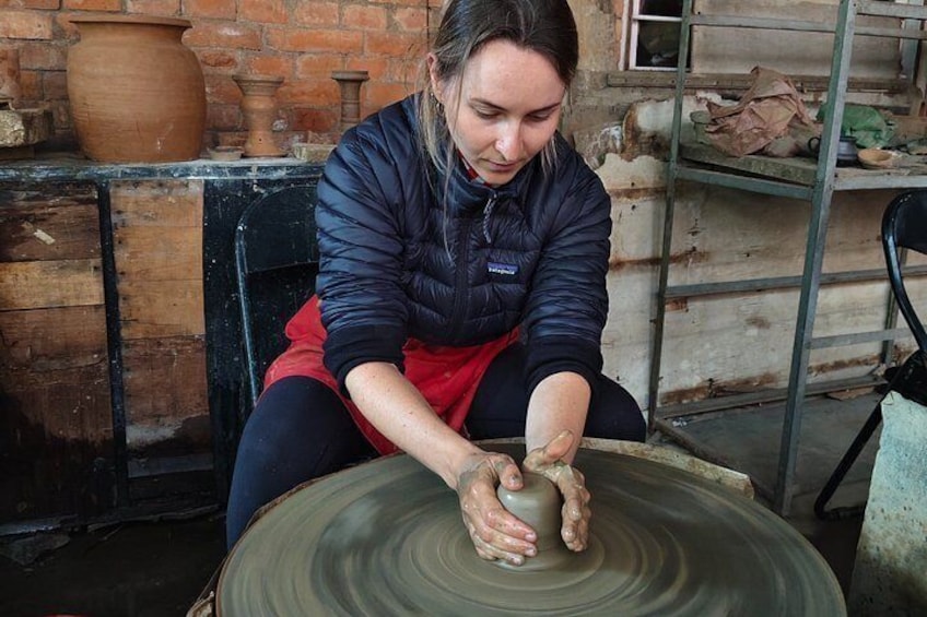 A person shaping a clay pot on a spinning wheel. 1