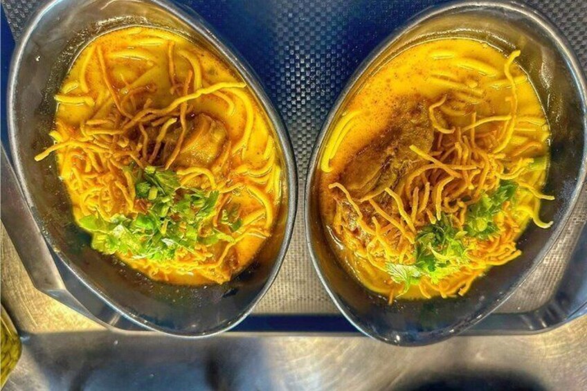 Two bowls of noodle soup with a clear broth, garnished with green herbs. 2