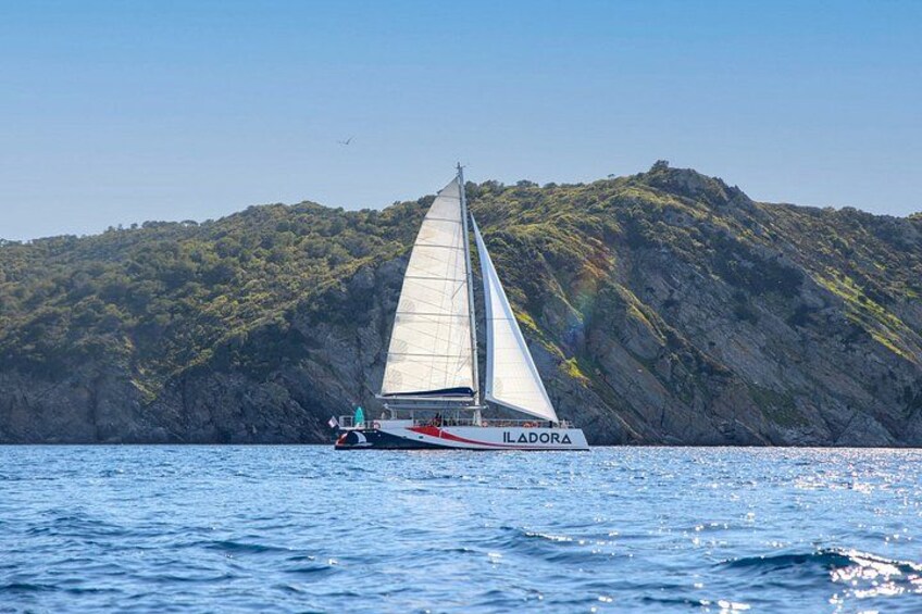 A sailboat named ILADORA on calm waters with a rocky coastline in the background. 5