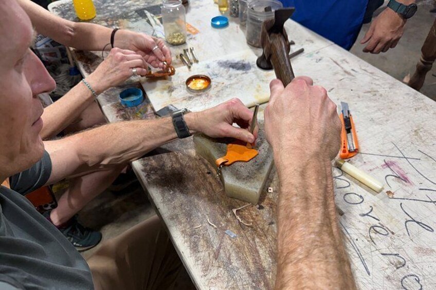 A person working with a hammer and a metal object on a workbench. 3