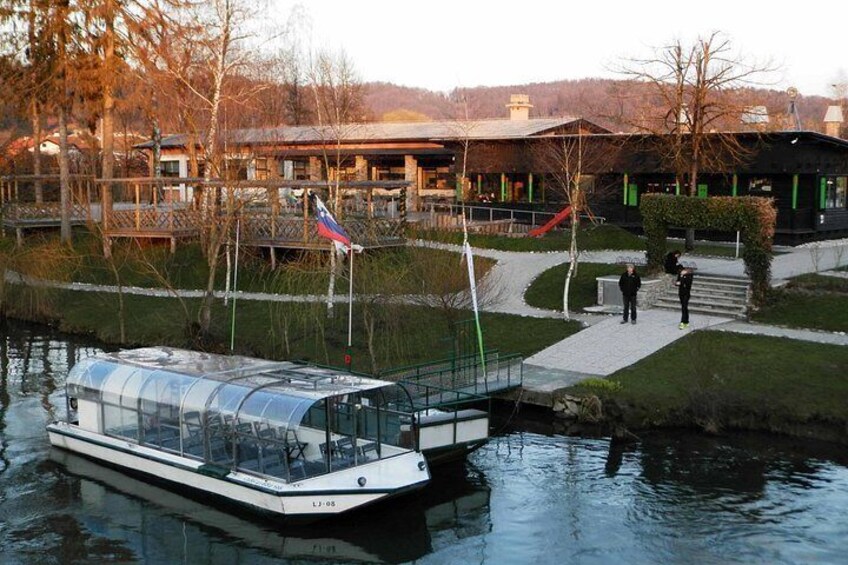 A riverboat docked at a pier, a building with a green roof, and a person walking on a path. 2