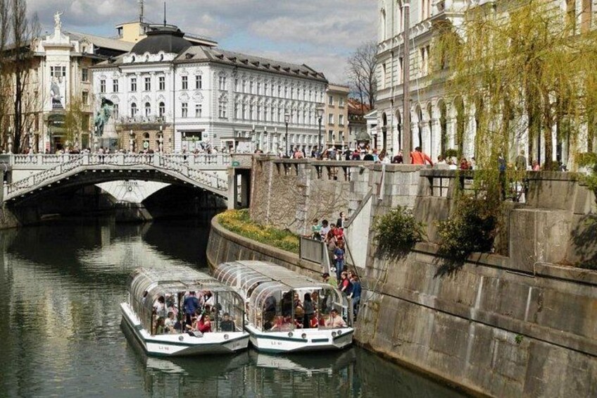 En kanal med två båtar, en bro och historiska byggnader. 1