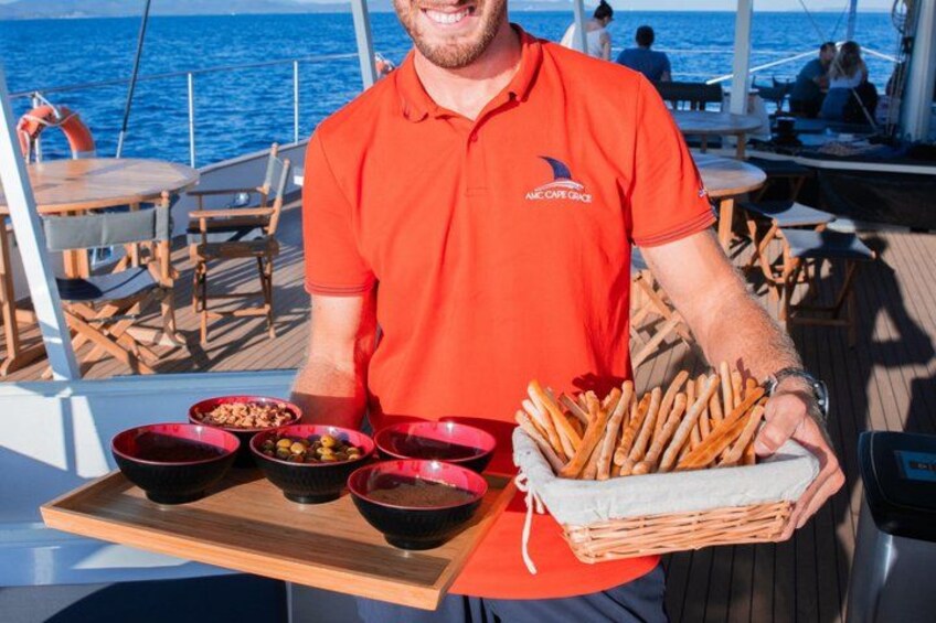 A person on a boat holding a tray with bowls of food and a basket of breadsticks. 5