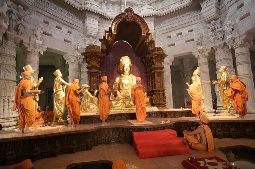 A temple interior with golden statues, intricate carvings, and a central ornate structure. 4