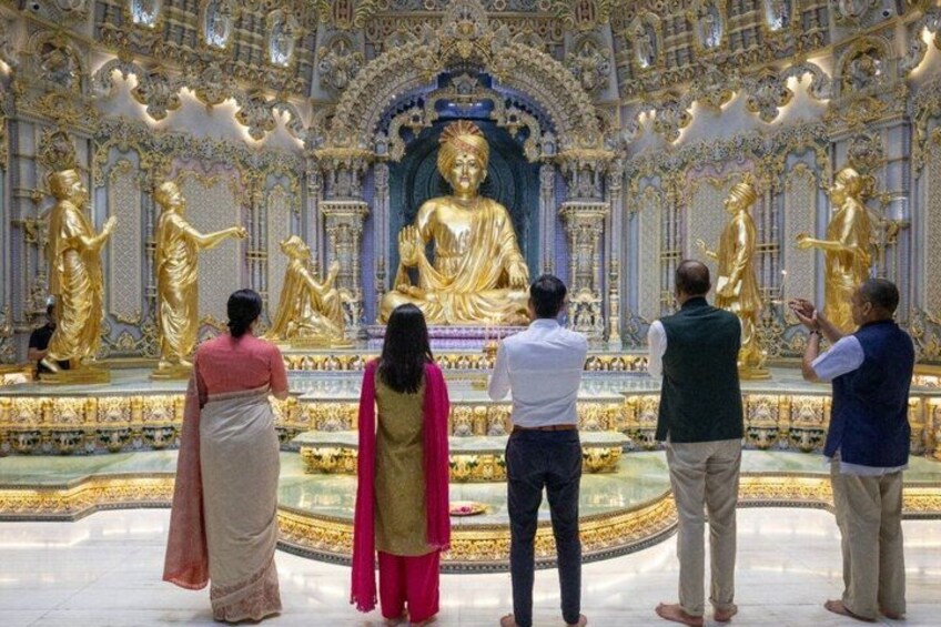 Eine Gruppe von Menschen in einem Tempel mit goldenen Statuen und aufwendiger Architektur. 3