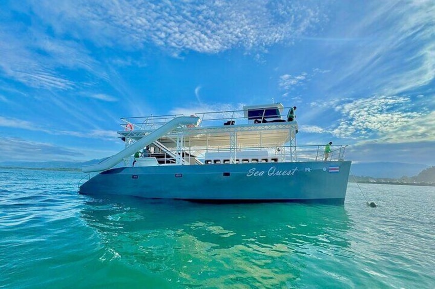 A boat named "Sea Quest" on turquoise water with a clear sky. 1