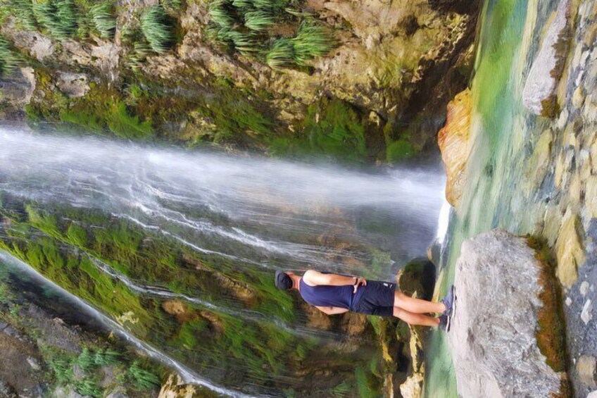 A person standing on a cliff overlooking a waterfall. 3