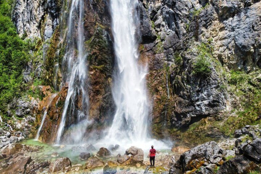 A waterfall cascading down a rocky cliff surrounded by greenery. 4
