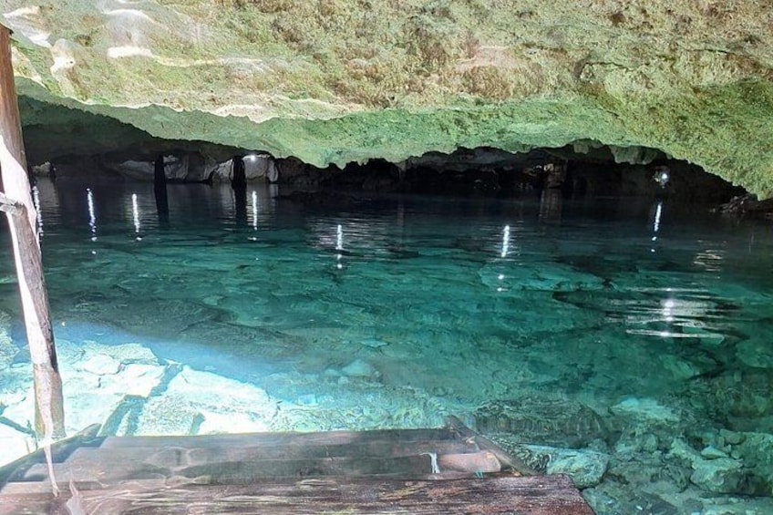 A cave with clear water, stalactites, and a wooden walkway. 5