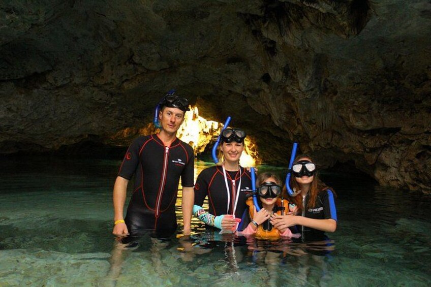 A group of people in a cave with clear water, wearing wetsuits and snorkels. 4