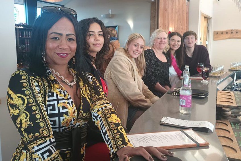 A group of people seated at a bar with a bottle of water and glasses on the table. 3