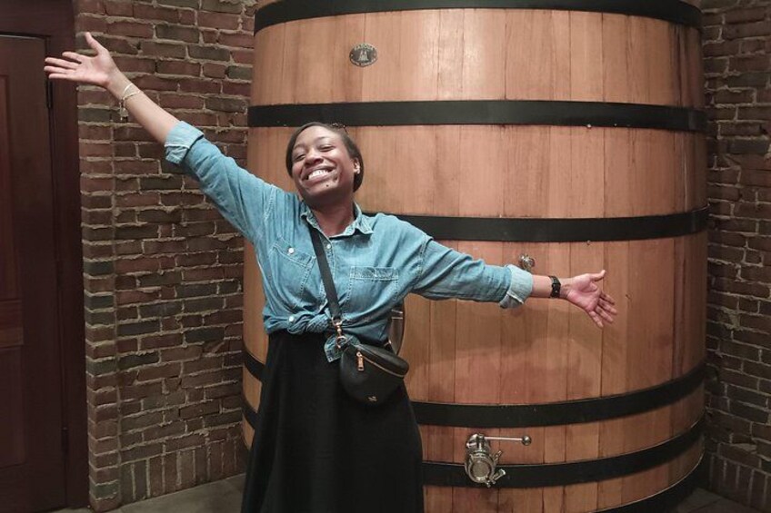 A person standing in front of a wooden barrel with arms outstretched. 2