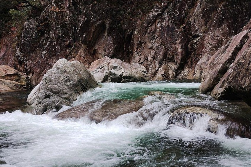 A river flowing through a rocky gorge with large boulders and steep cliffs. 2
