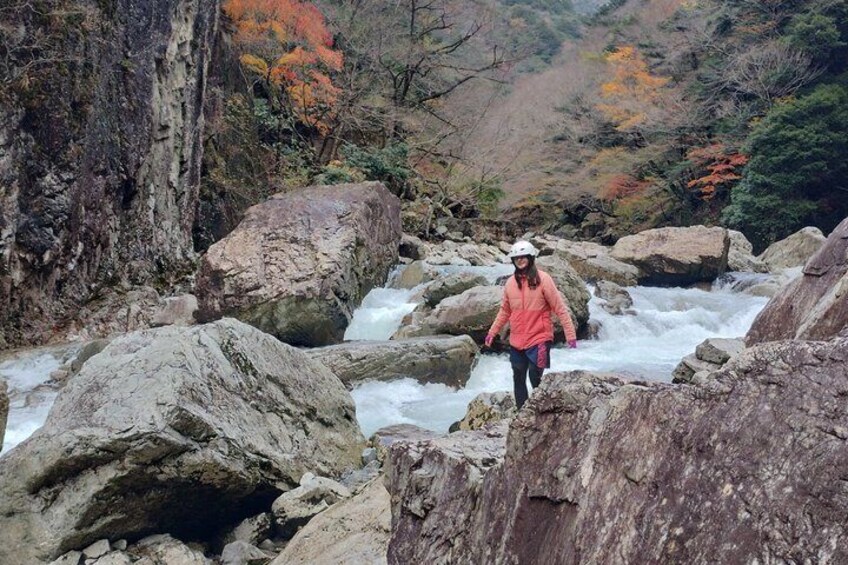Une personne qui fait de la randonnée dans un ruisseau rocheux, avec le feuillage automnal en arrière-plan. 5