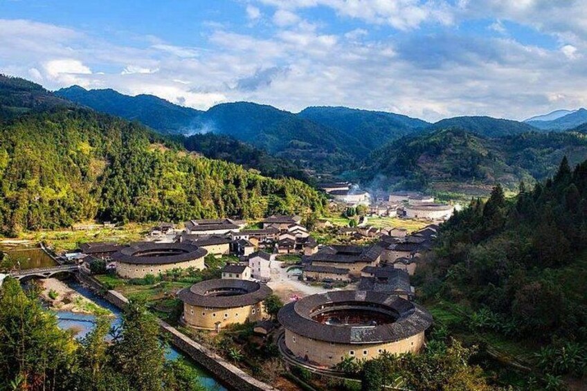 A traditional village with circular buildings surrounded by lush green mountains. 1