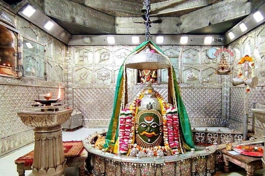 A temple interior with a central deity, ornate decorations, and a hanging lamp. 2