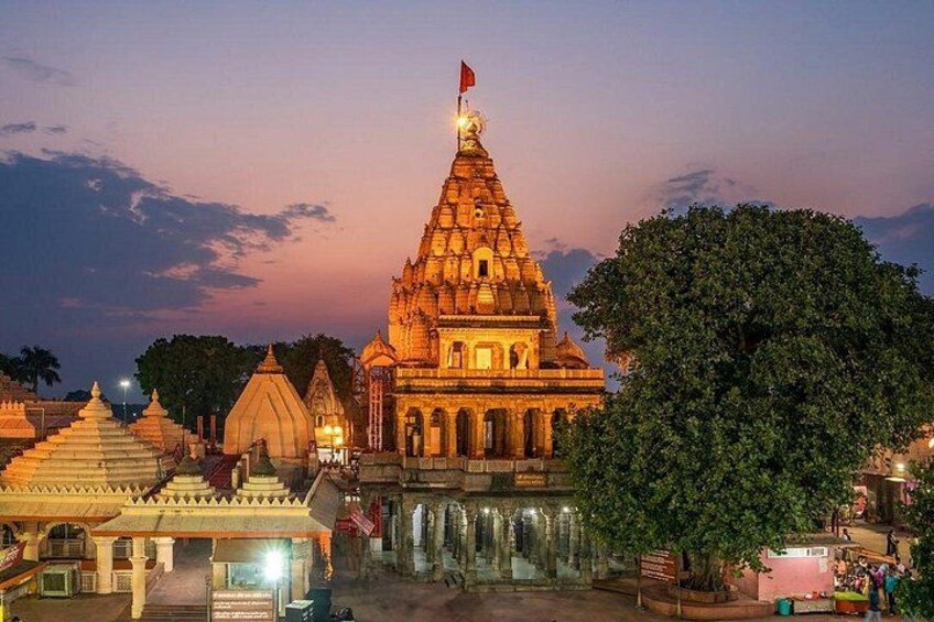 A temple complex with a prominent spire, smaller shrines, and a large tree. 1