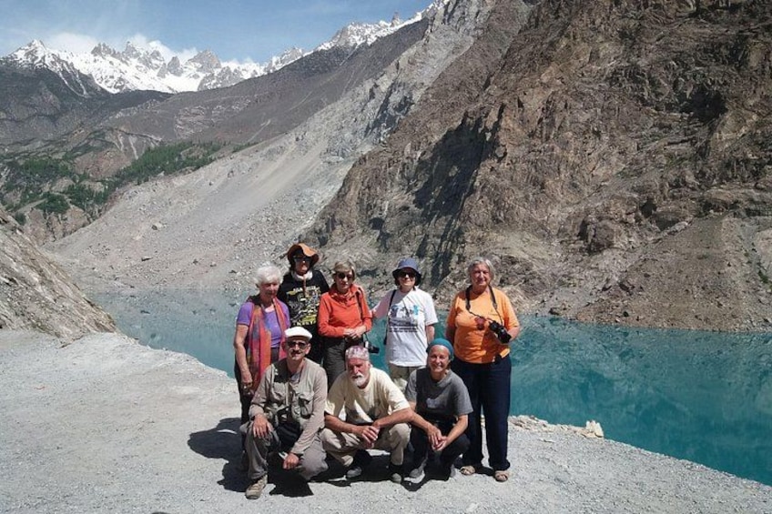Un grupo de personas posando en un risco con una montaña y un lago al fondo. 1