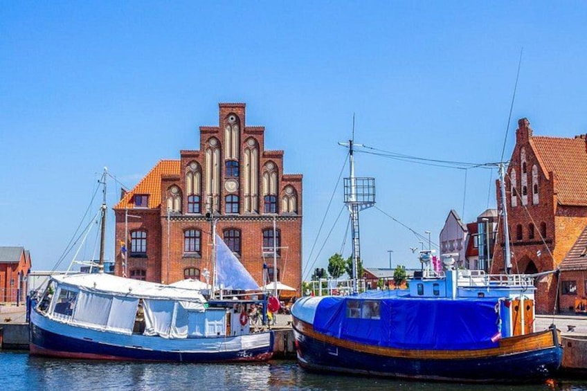 A blue boat docked at a pier with a historic building in the background. 4