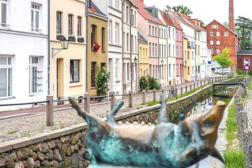 A canal with buildings on one side and a statue in the foreground. 3