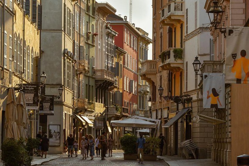 Una stretta via fiancheggiata da edifici storici, un caffè e una persona che cammina. 2