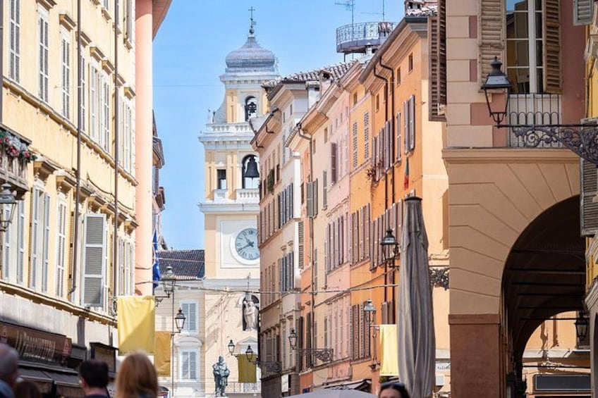 Una strada con edifici storici, una torre dell'orologio e un arco. 5
