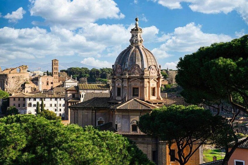 Un edificio storico con una cupola, circondato da alberi e altri edifici. 1