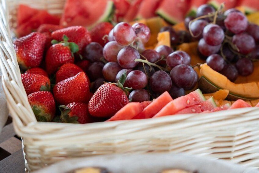 A wicker basket filled with strawberries, grapes, watermelon, and cantaloupe. 4