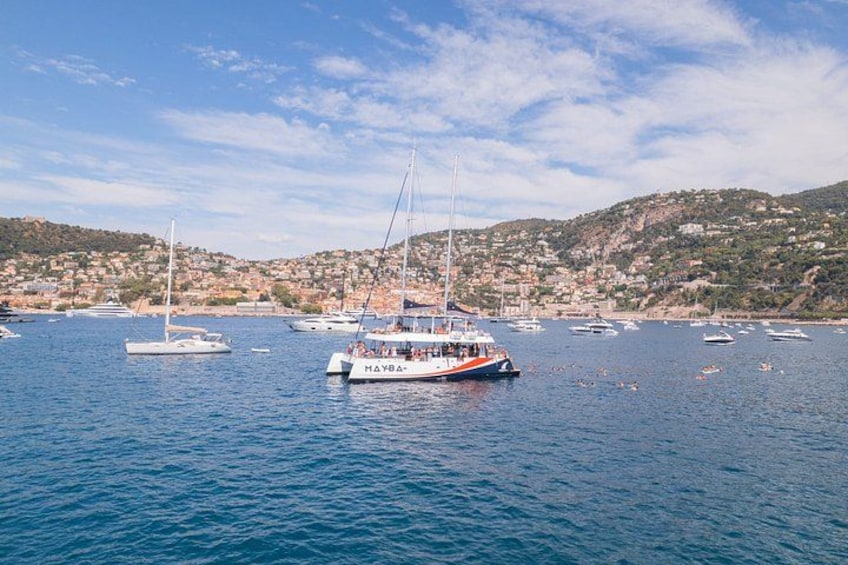 A coastal town with boats on the water, a hill with buildings, and a clear sky. 3