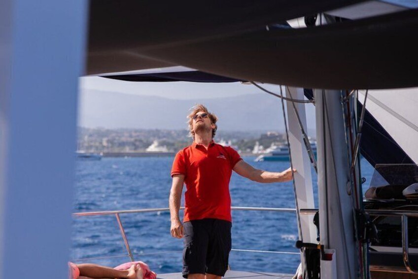 A person in a red shirt standing on a boat with a view of the sea and distant land. 2