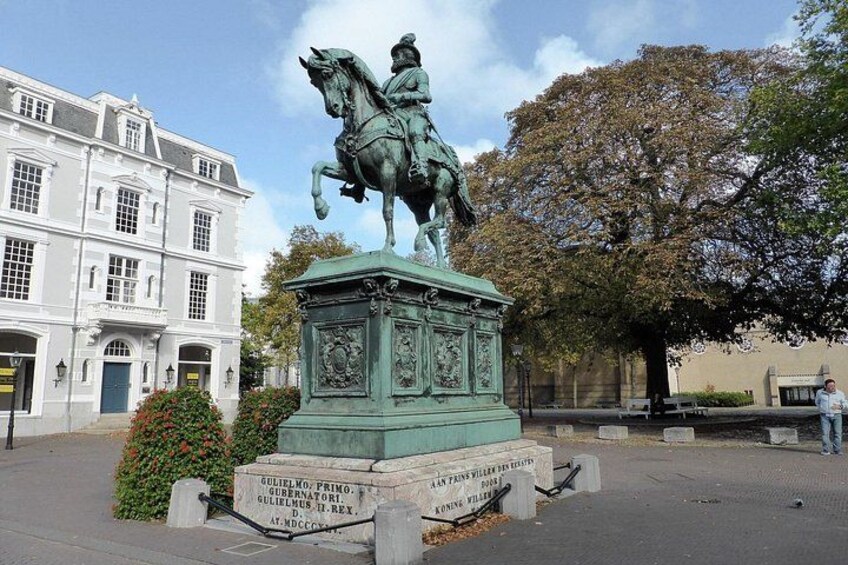 En staty föreställande en man till häst på ett torg, med en byggnad i bakgrunden. 1