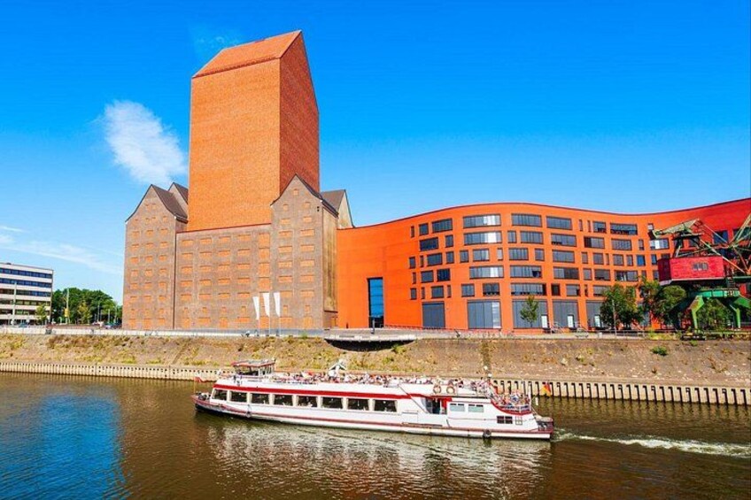 Un río con una embarcación blanca, un edificio de ladrillo rojo y un cielo azul despejado. 2