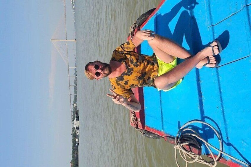 Una persona sentada en un bote con cubierta azul, vestida con una camisa amarilla y lentes de sol. 5