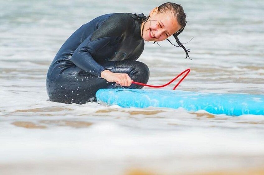 A person in a wetsuit kneeling on a blue surfboard in the ocean. 1