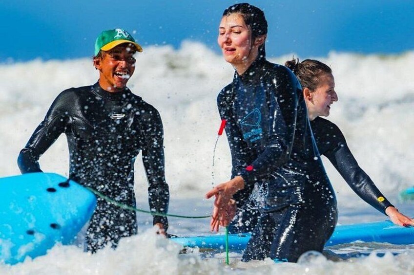 People in wetsuits on a surfboard in the ocean. 5
