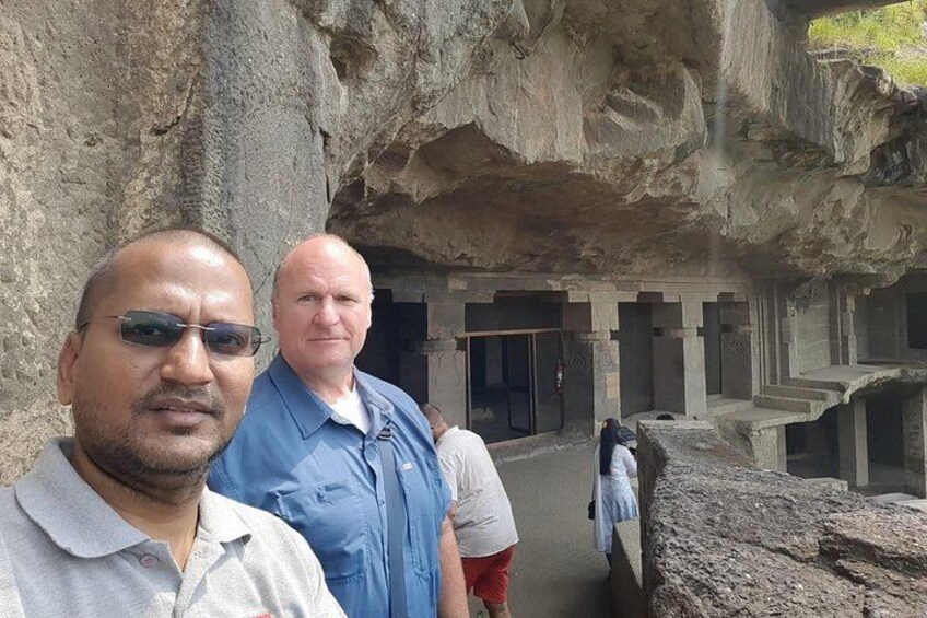 A cave with carved stone structures and a person standing in the foreground. 5