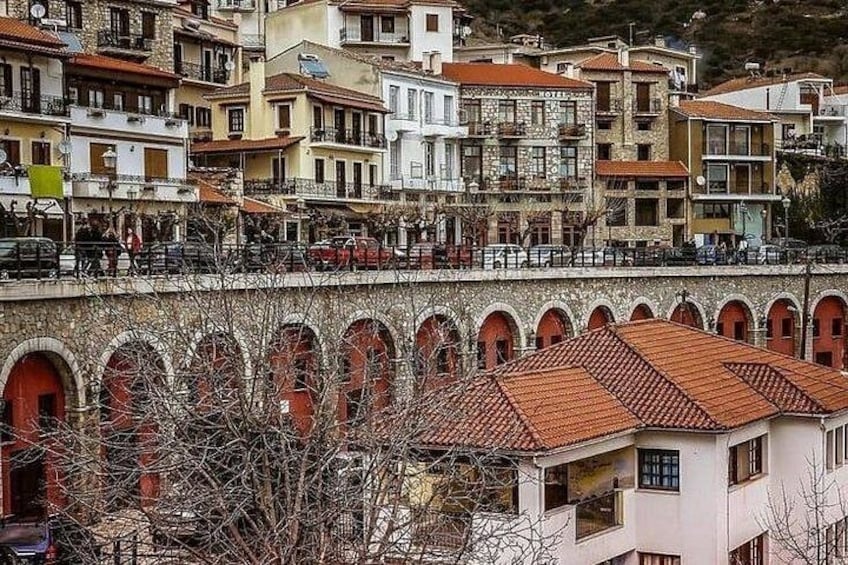 A town with historic buildings, a bridge, and a stone wall with arches. 3