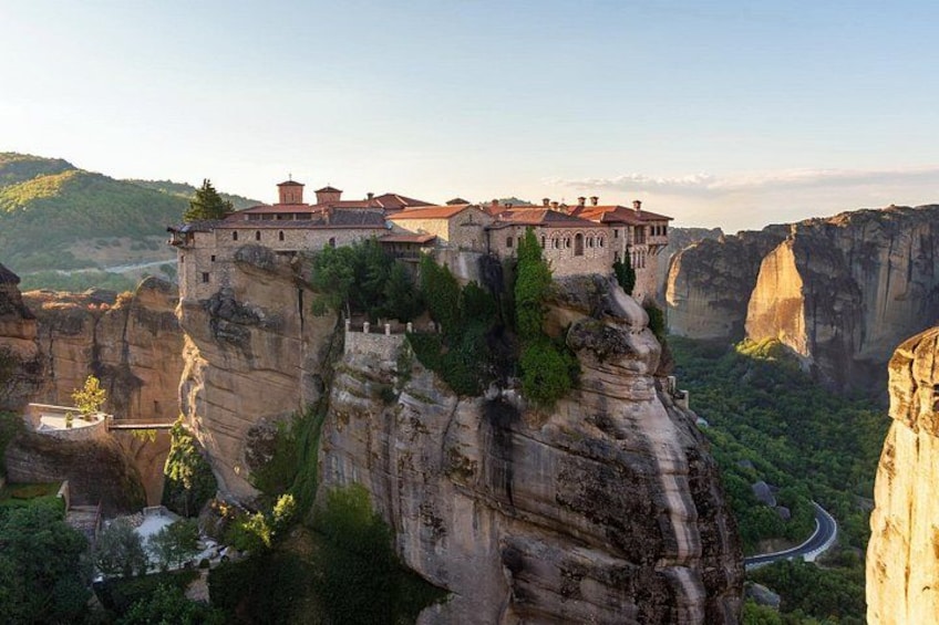 A monastery perched on a cliff, surrounded by lush greenery and dramatic rock formations. 1