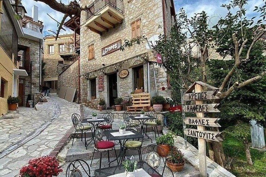 A stone building with a café, outdoor seating, and directional signs. 4