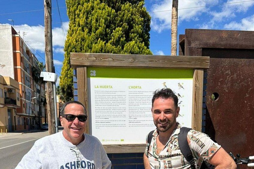 Zwei Männer stehen vor einem Schild mit Text und Illustrationen. 3