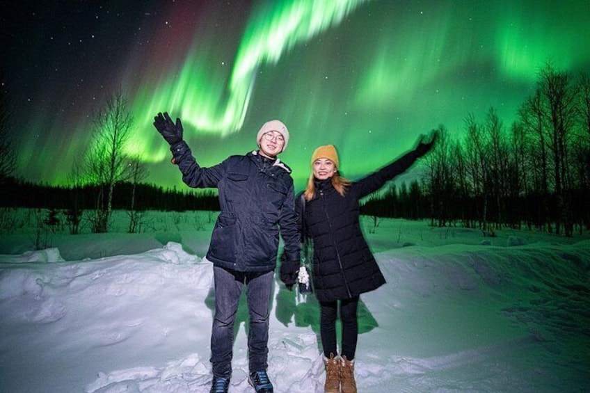 A person standing on snow with a green aurora in the background. 4