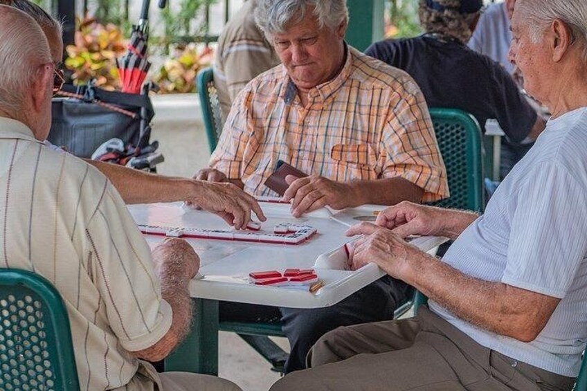 Three people sitting at a table with a deck of cards. 2