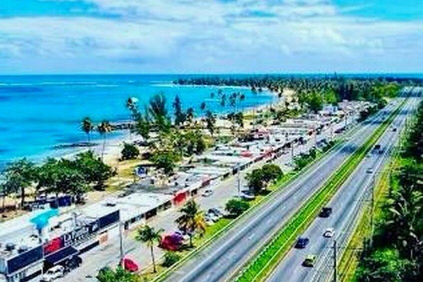 Una autopista costera con vehículos, una playa y palmeras. 2